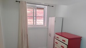 A room with a window, a white wardrobe, and a red cabinet.