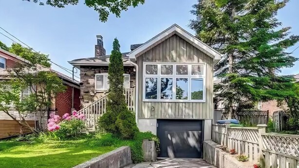 A two-story house with a garage, a front yard with a small pond, and a wooden fence.