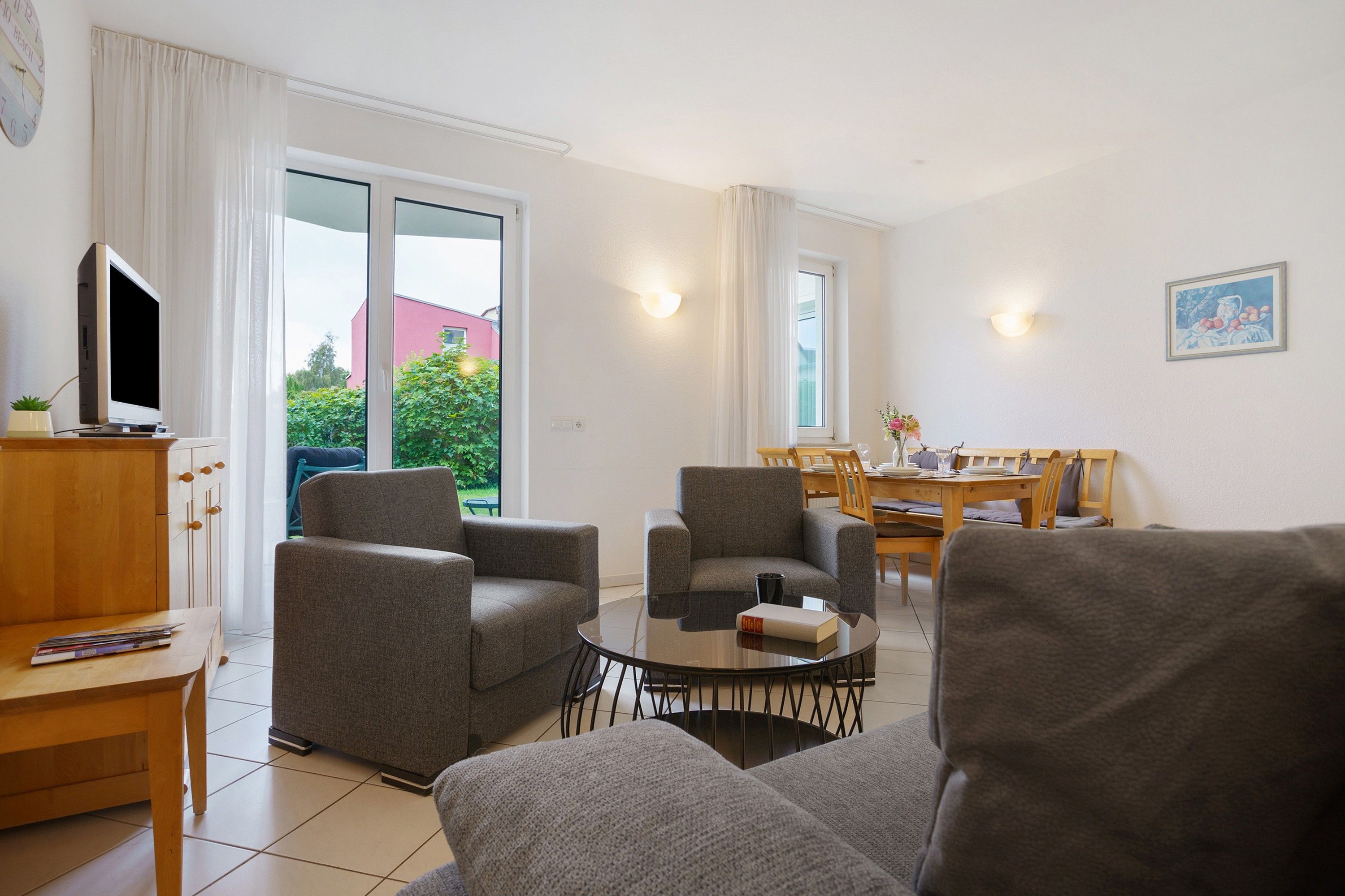 Un salon moderne avec des canapés gris, une table basse et un téléviseur à écran plat posé sur un meuble en bois.