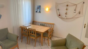 Una stanza con un tavolo da pranzo in legno, quattro sedie, un divano verde, una lampada a parete e una decorazione a tema nautico.