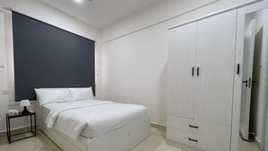 A bedroom with a bed, a nightstand, a wardrobe, and a ceiling fan. - Cozy 1BR Apt in Hulhumale, Maldives - AC/WiFi (Hulhumale)