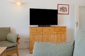 A living room with a television on a wooden cabinet, a sofa, and a chair. - Apartment 'Seestern' with Balcony and Wi-Fi (Zempin)