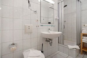 Un baño moderno con lavamanos, espejo y ducha blancos.