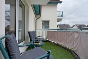 A balcony with a glass table, two chairs, and a small window. - Apartment 'Seestern' with Balcony and Wi-Fi (Zempin)