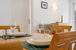 Una mesa de comedor dispuesta con platos, vasos y cubiertos, con una silla al frente.