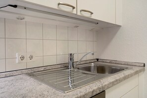 Cozinha com pia de aço inoxid ável, duas tomadas elétricas e bancada de granito.