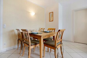 A dining area with a wooden table and chairs, a light fixture on the wall, and a framed picture. - Apartment 'Seestern' with Balcony and Wi-Fi (Zempin)