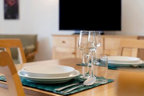A dining table set with plates, glasses, and cutlery, with a television in the background. - Apartment 'Seestern' with Balcony and Wi-Fi (Zempin)