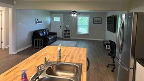 A modern kitchen with a wooden island, stainless steel sink, and a refrigerator.