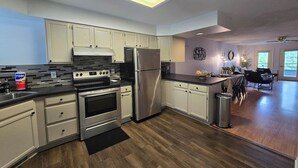 A modern kitchen with white cabinets, stainless steel appliances, and a black countertop.