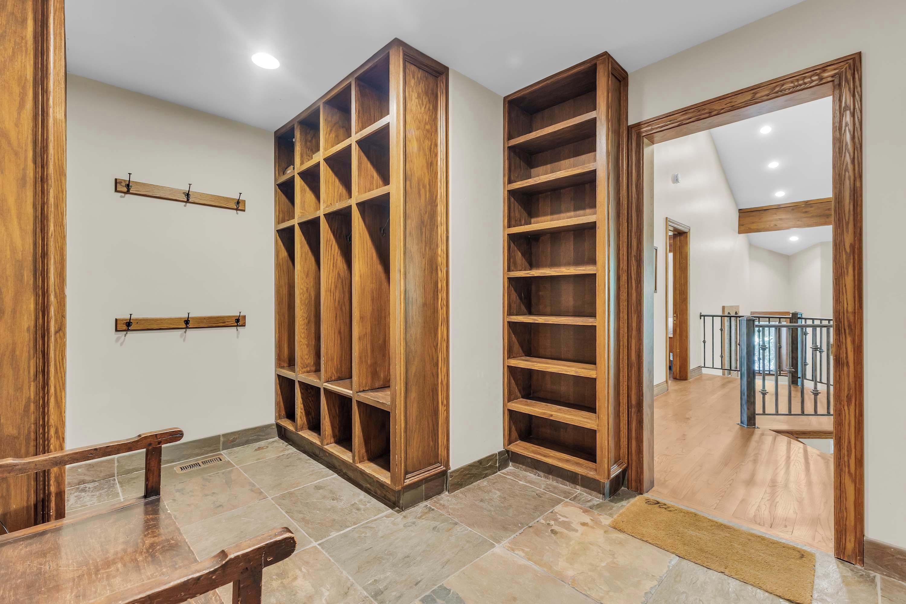Une pièce avec un banc en bois, une bibliothèque intégrée en bois et un grand miroir.