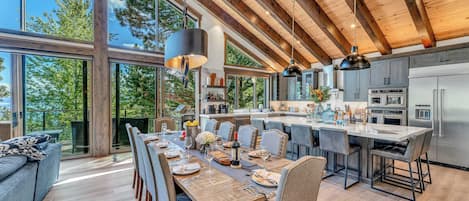 A modern kitchen with a large island, stainless steel appliances, and a dining area with a long table and chairs.