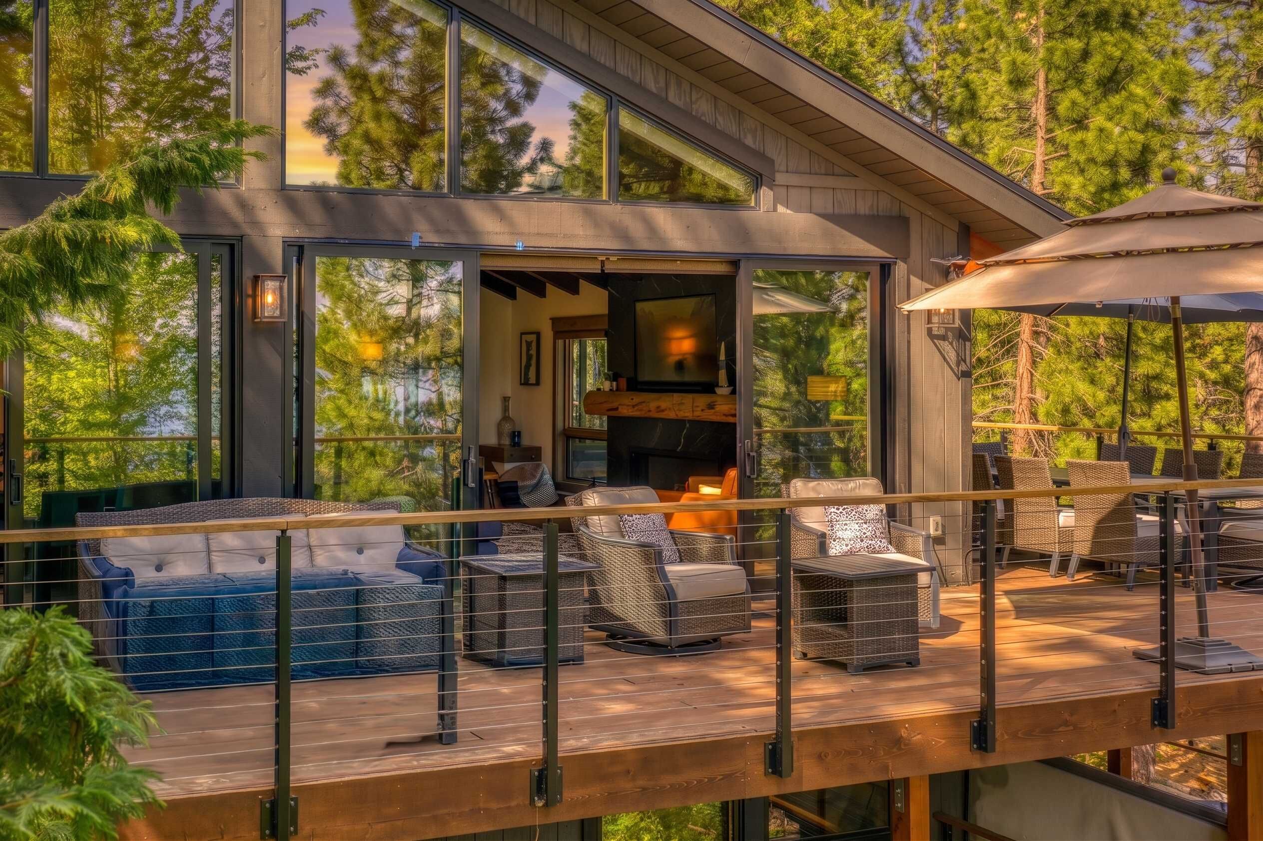 A modern outdoor deck with wicker furniture and a glass enclosure.