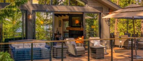 A modern outdoor deck with wicker furniture and a glass enclosure.