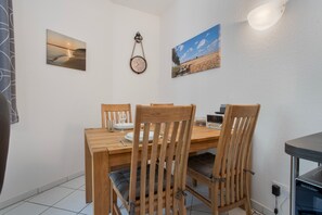 A dining area with a wooden table and chairs, a wall-mounted clock, and two framed pictures. - Apartment Ariane with Wi-Fi (Zempin)