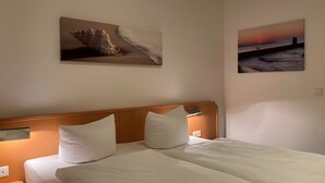 A hotel room with a bed, two pillows, a nightstand, and two wall-mounted paintings. - Apartment Ariane with Wi-Fi (Zempin)
