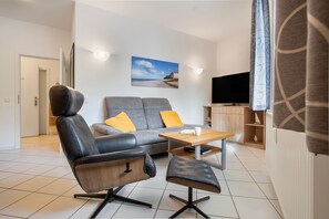 Ein modernes Wohnzimmer mit einer Couch, einem Ledersessel, einem Couchtisch und einem Fernseher.