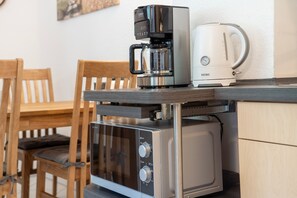 Eine kompakte Küchenzeile mit Kaffeemaschine, Toaster und Mikrowelle.