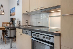 Eine moderne Küche mit Einbauofen, Kaffeemaschine und Spüle.