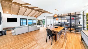 A spacious living area with a wooden ceiling, a dining table, and a sofa. - Front Row to the Pacific - Bird Rock 3BR (San Diego)