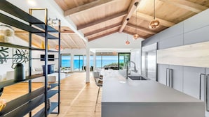 A modern kitchen with a large island, wooden ceiling beams, and a view of the sea. - Front Row to the Pacific - Bird Rock 3BR (San Diego)