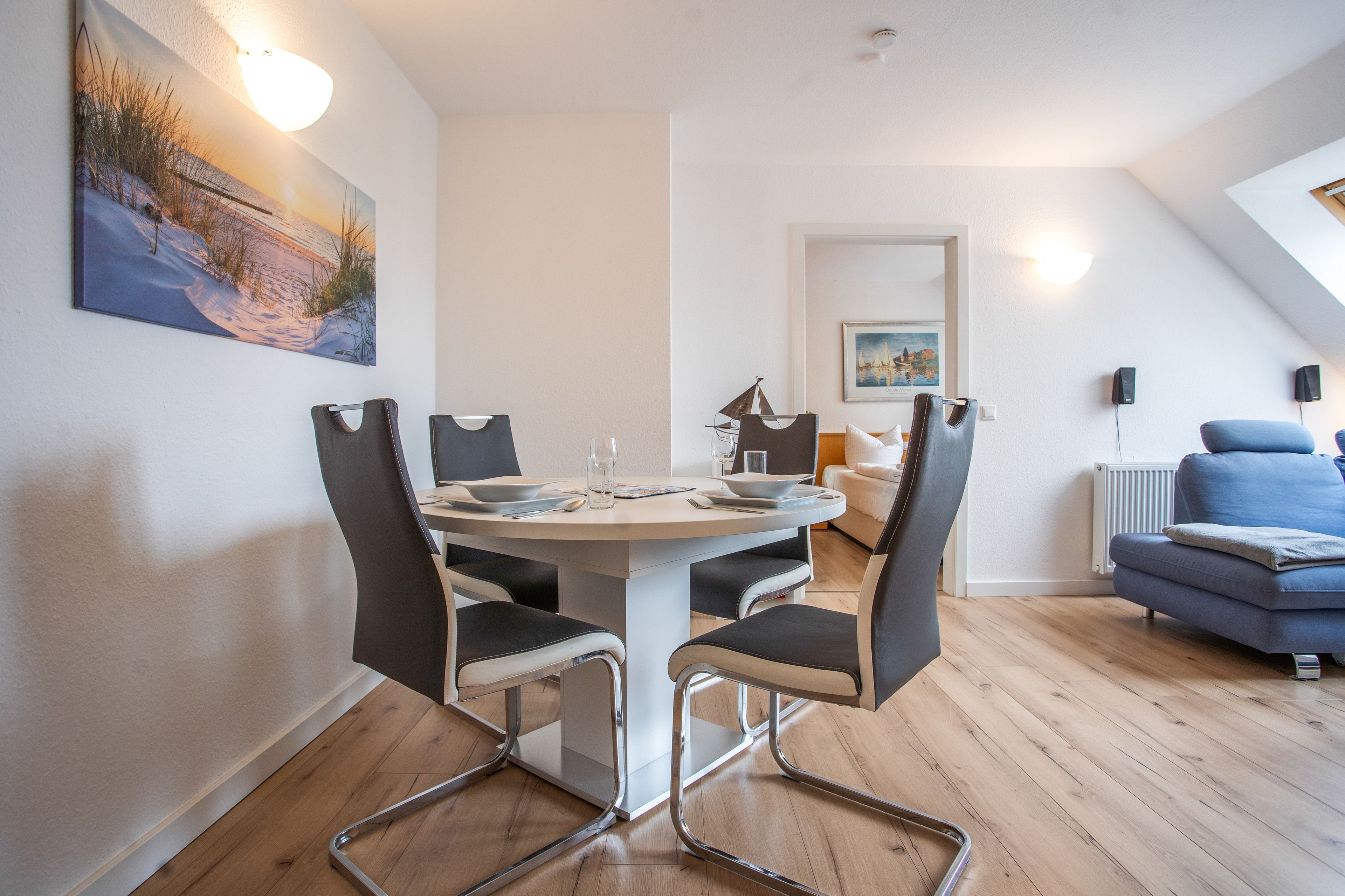 Un espace repas moderne avec une table ronde, des chaises et un tableau accroché au mur.