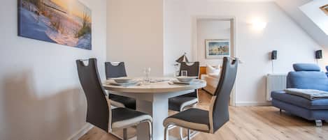 Un'area pranzo moderna con un tavolo rotondo, sedie e un quadro appeso al muro.