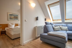 A modern room with a bed, a blue sofa, a radiator, and a painting on the wall. - Apartment 'Bella' with Balcony and Wi-Fi (Zempin)
