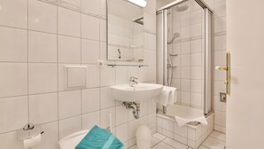 Uma casa de banho moderna com lavatório, espelho e chuveiro.