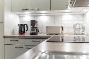 Ett modernt kök med en kaffebryggare, brödrost och ett hyllsystem för glas.