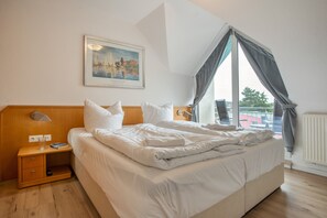 A hotel room with a large bed, a bedside table, a nightstand, a window with curtains, and a painting on the wall. - Apartment "Bella" with Balcony and Wi-Fi (Zempin)