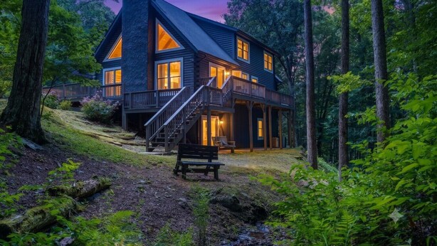 A cabin with a deck, stairs, and a bench in a forest. - Ripple Creek Lodge | Mtn Cabin & Firepit (Cullowhee)