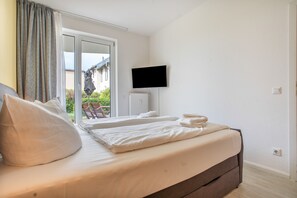 A hotel room with a bed, a television, and a view of the outside. - Apartment 'Strandnah' with Private Terrace and Wi-Fi (Zempin)
