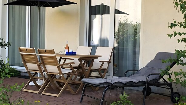 An outdoor patio with a table, chairs, and a lounge chair. - Apartment “Strandnah” with Private Terrace and Wi-Fi (Zempin)