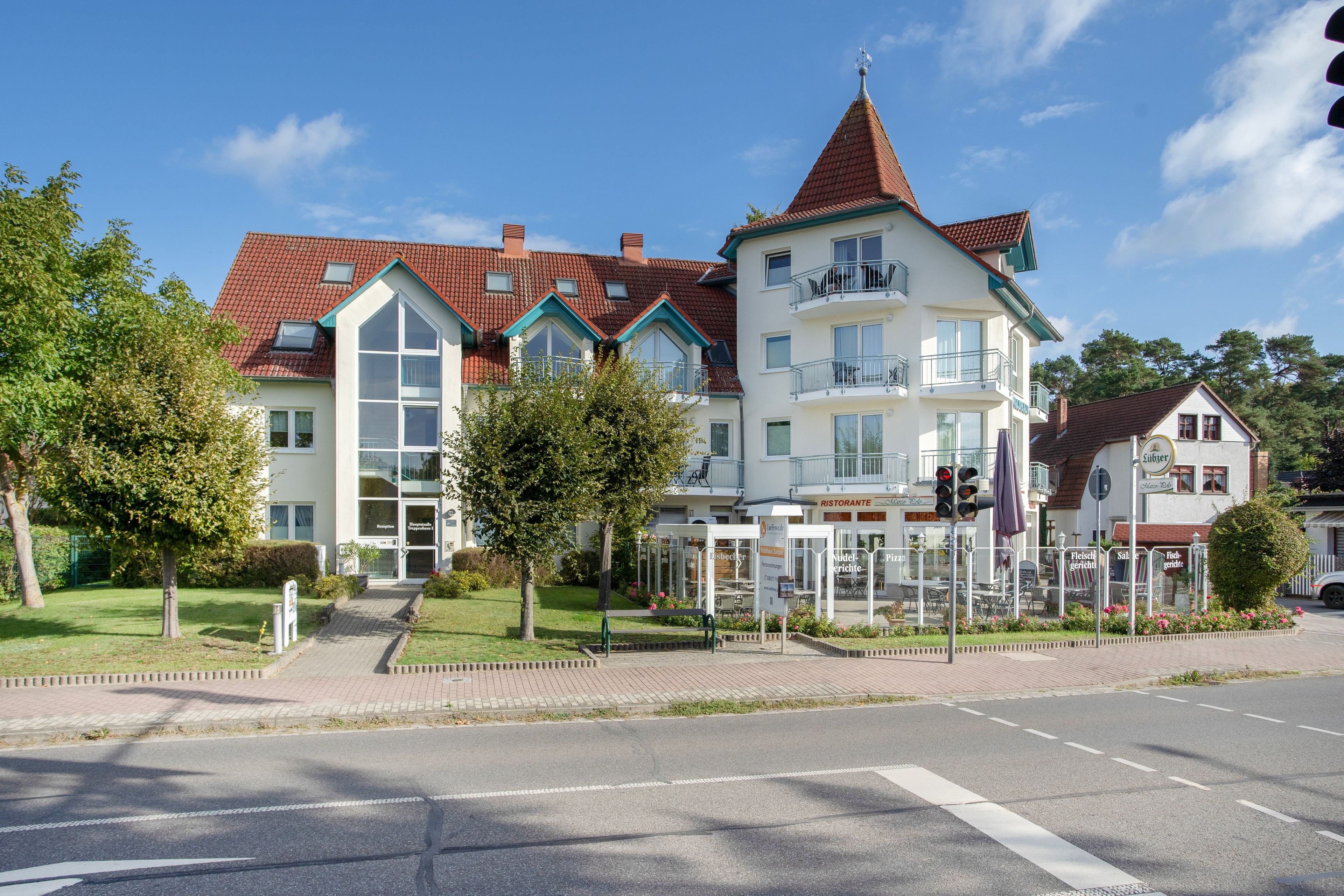 Ein mehrgeschossiges Gebäude mit rotem Ziegeldach, einem zentralen Turm und einer Rezeption.