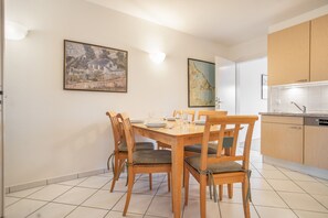 A dining area with a wooden table and chairs, a map on the wall, and a kitchen in the background. - Apartment 'Stefanie - Bilder Alt' with Balcony and Wi-Fi (Zempin)