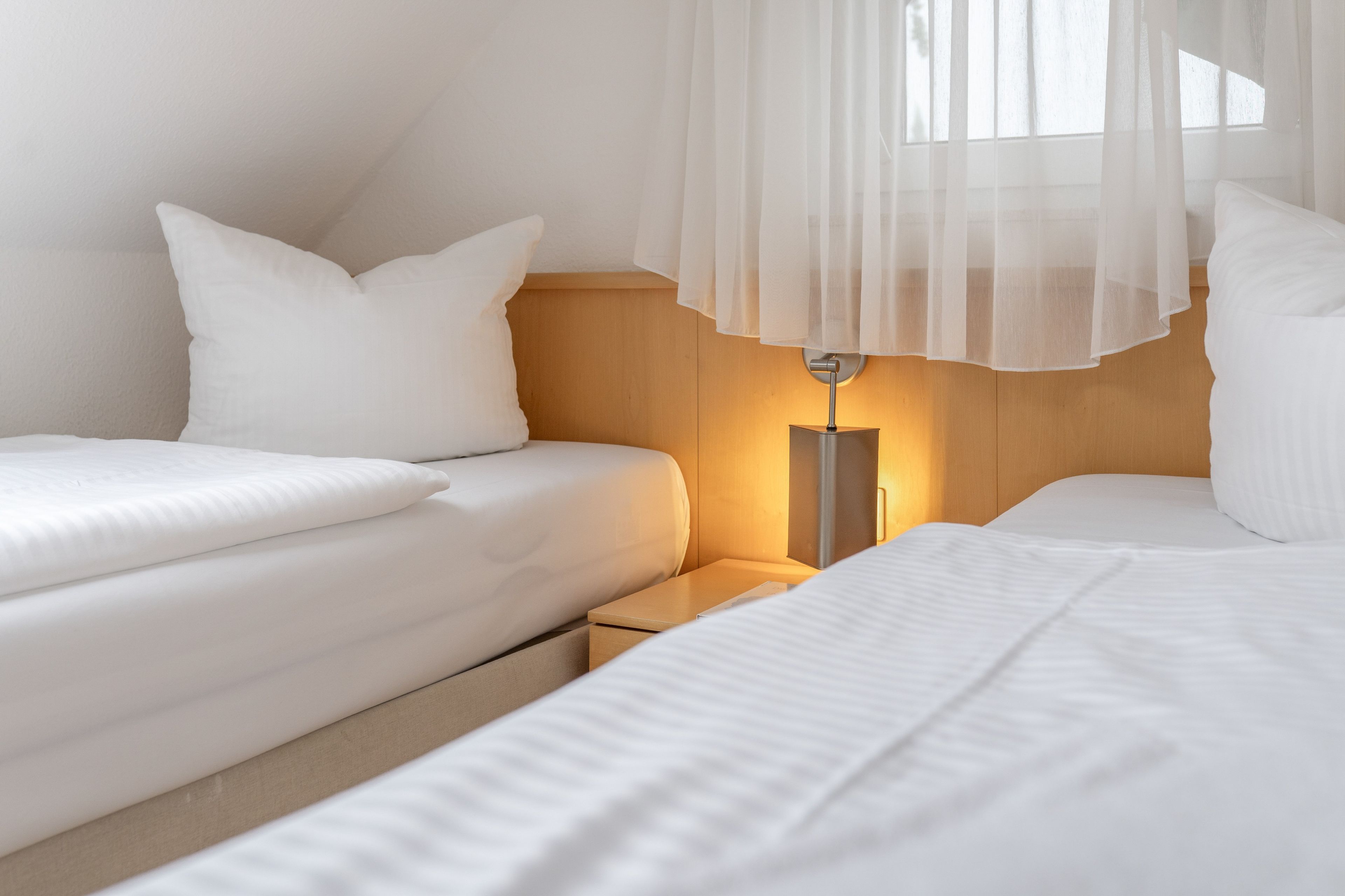 Une chambre avec deux lits, une table de chevet et une lampe.