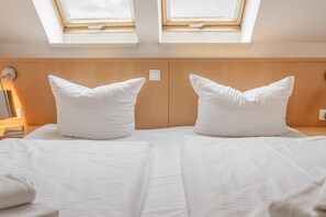 A hotel room with two beds, each with a pillow and a bedside table. There are skylights above the beds. - Apartment 'Stefanie - Bilder Alt' with Balcony and Wi-Fi (Zempin)