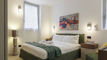 Een moderne slaapkamer met een bed, nachtkastjes, een lamp en een schilderij aan de muur.