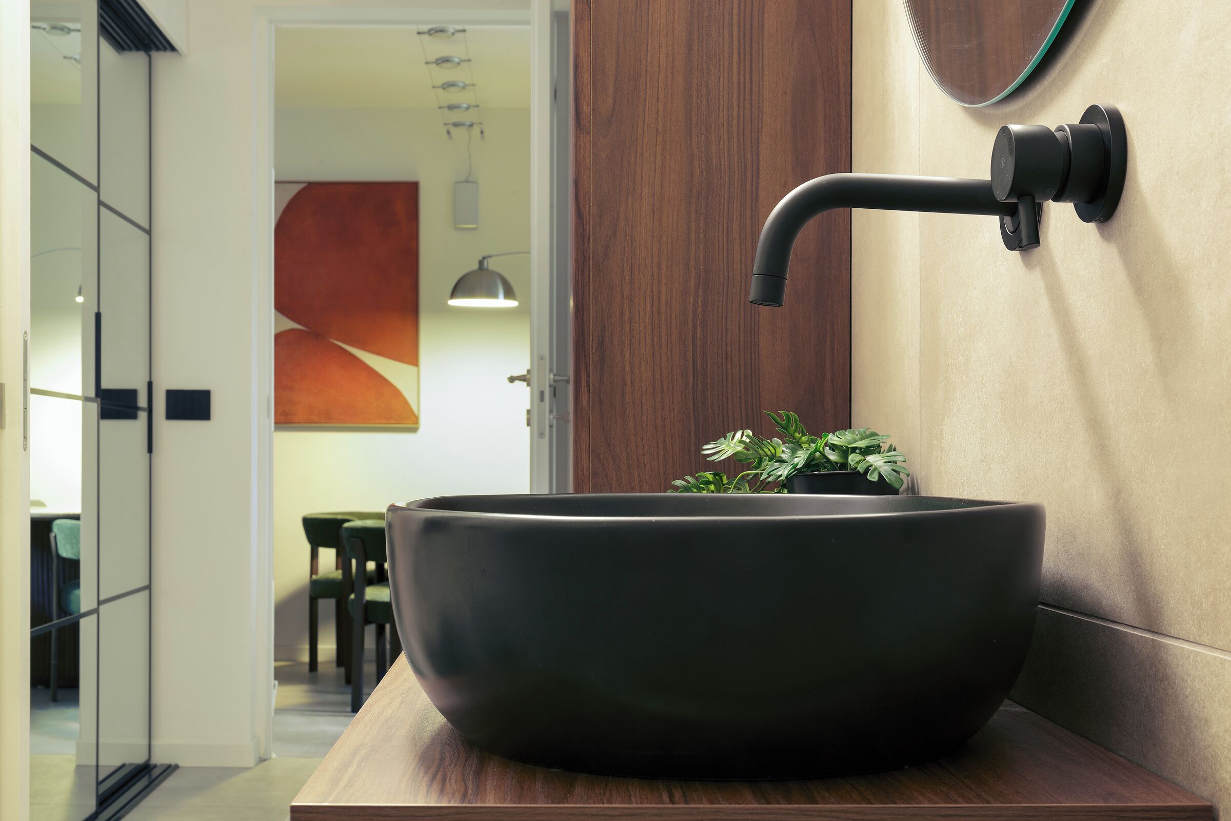 A modern bathroom with a large, dark-colored vessel sink mounted on a wooden countertop.