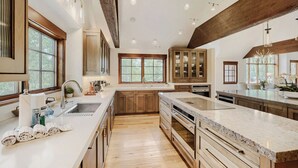 A spacious kitchen with wooden cabinets, a large island, and a view of the outdoors through large windows. - Escape to the heart of the Rockies! Luxury 5 bedroom home in Silverthorne! (Silverthorne)