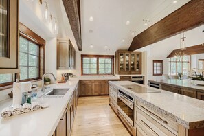 A spacious kitchen with wooden cabinets, a large island, and a view of the outdoors through large windows. - Escape to the heart of the Rockies! Luxury 5 bedroom home in Silverthorne! (Silverthorne)