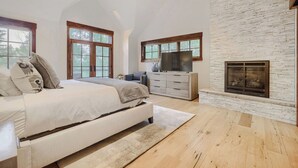 A bedroom with a bed, dresser, TV, fireplace, and large windows. - Escape to the heart of the Rockies! Luxury 5 bedroom home in Silverthorne! (Silverthorne)