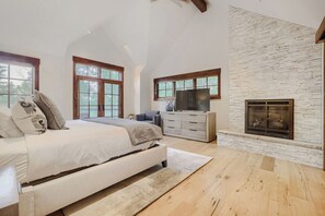 A bedroom with a bed, dresser, TV, fireplace, and large windows. - Escape to the heart of the Rockies! Luxury 5 bedroom home in Silverthorne! (Silverthorne)
