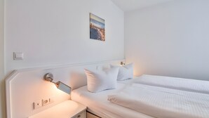 Une chambre d’hôtel avec un lit, une table de chevet, une lampe fixée au mur et un tableau.