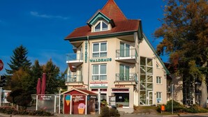 Un immeuble à plusieurs étages qui abrite un restaurant, une pizzeria et un café au rez-de-chaussée.