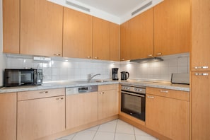 Een moderne keuken met houten kastjes, een magnetron, een koffiezetapparaat en een vaatwasser.