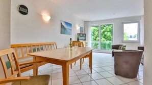 Un coin repas avec une table et des chaises en bois, une horloge et un téléviseur.