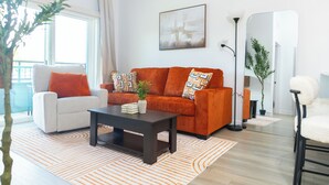Ein Wohnzimmer mit einer Couch, einem Sessel, einem Couchtisch und einer Zimmerpflanze.