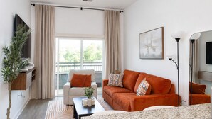 Ein modernes Wohnzimmer mit einer Couch, einem Sessel und einem Flachbildfernseher.